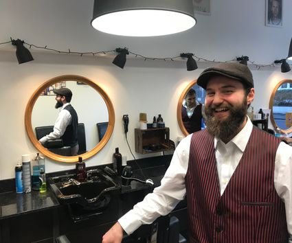 A barber welcoming customers at The Cut