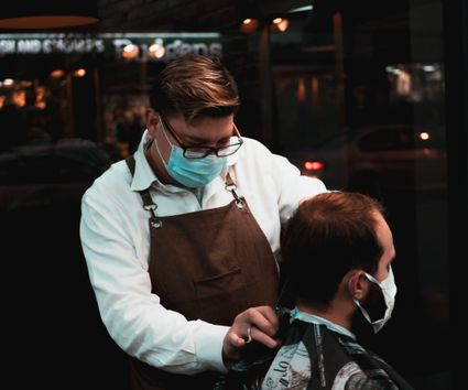 A barber carefully finishing a haircut